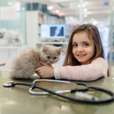 A young person smiles while holding a fluffy kitten